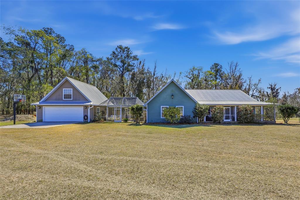 A screened-in porch with green siding, concrete flooring, and two wooden Adirondack chairs — 27471 NW 173RD TERRACE, ALACHUA, FL