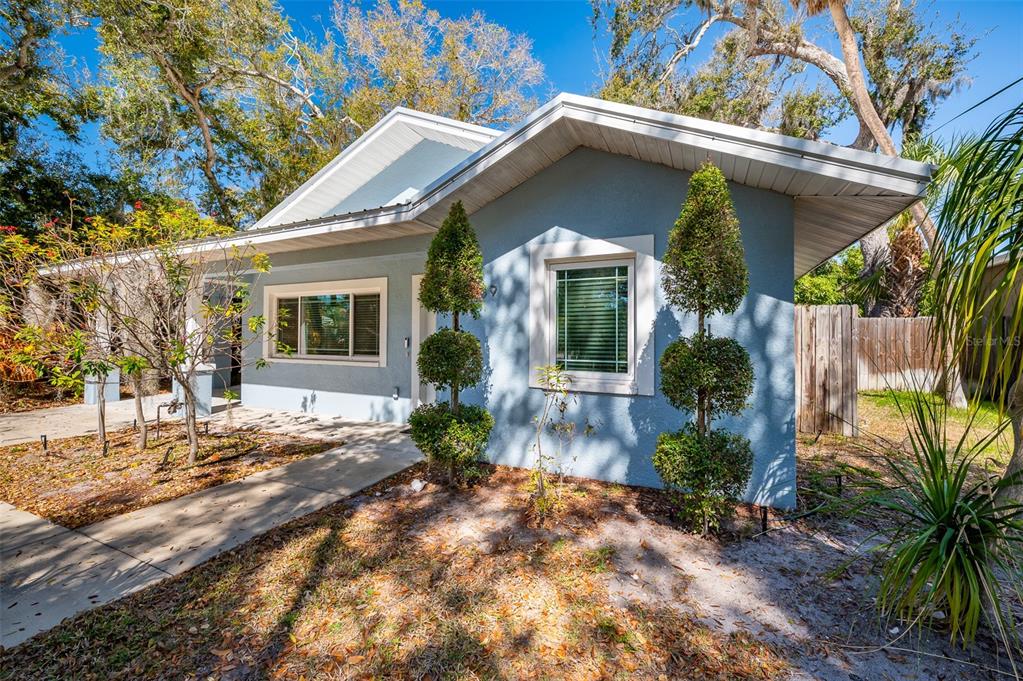 A light blue single-story house features a concrete walkway and two tiered topiary trees — 1039 23RD STREET, SARASOTA, FL