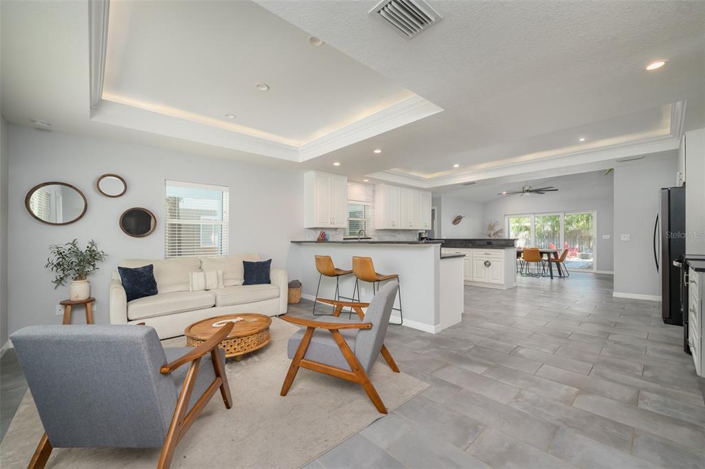 An open-concept living room and kitchen featuring gray tile floors and a tray ceiling — 1039 23RD STREET, SARASOTA, FL