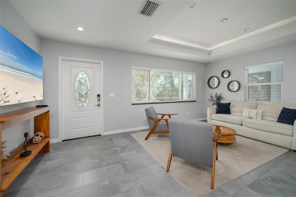 A living room features gray tile flooring, a white sofa, two armchairs, and a television — 1039 23RD STREET, SARASOTA, FL