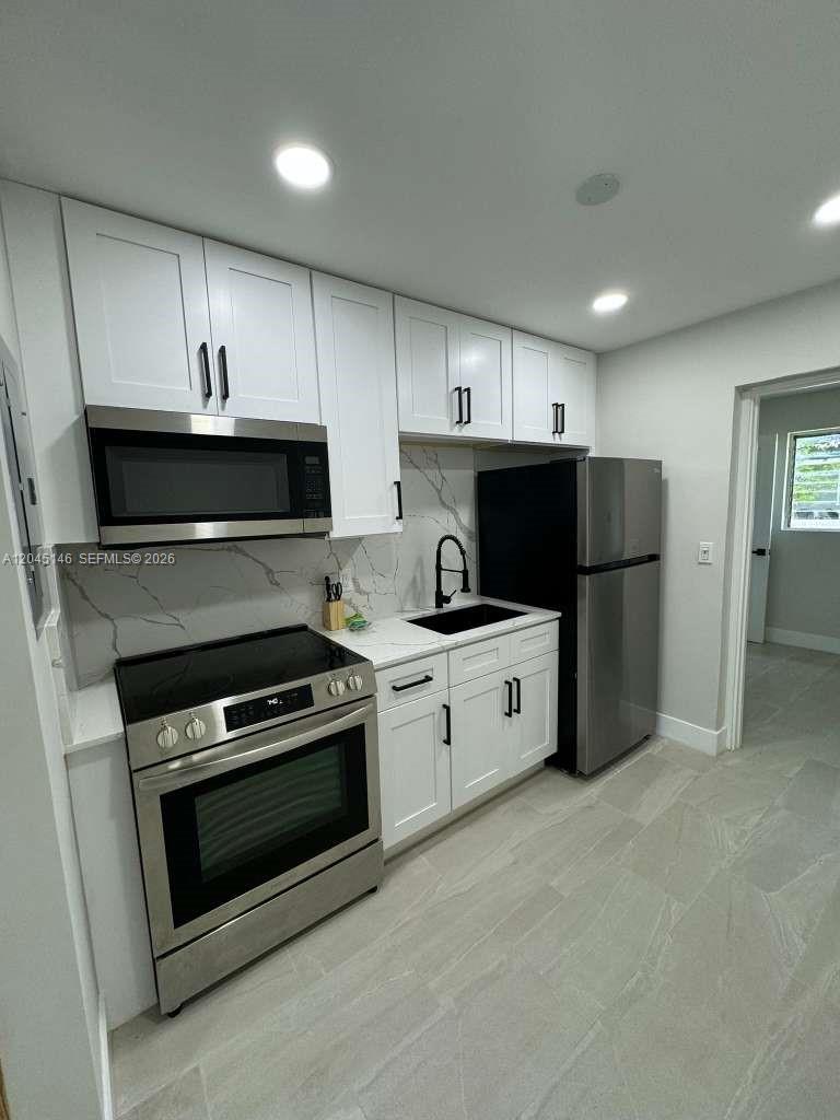 A modern kitchen features white cabinets, stainless steel appliances, and a marble-patterned backsplash — 4708 SW 33rd Ave # 4708, Dania Beach FL 33312, DANIA BEACH, FL