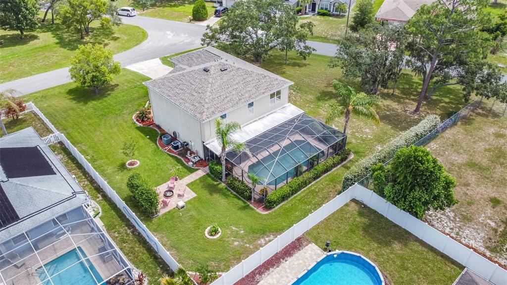 An aerial view shows a two-story house with a screened pool and fenced backyard — 10446 AVILA STREET, SPRING HILL, FL