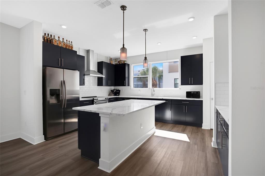 A modern kitchen features dark cabinetry, a white marble island, and stainless steel appliances — 2506 W CLEVELAND STREET UNIT 9, TAMPA, FL