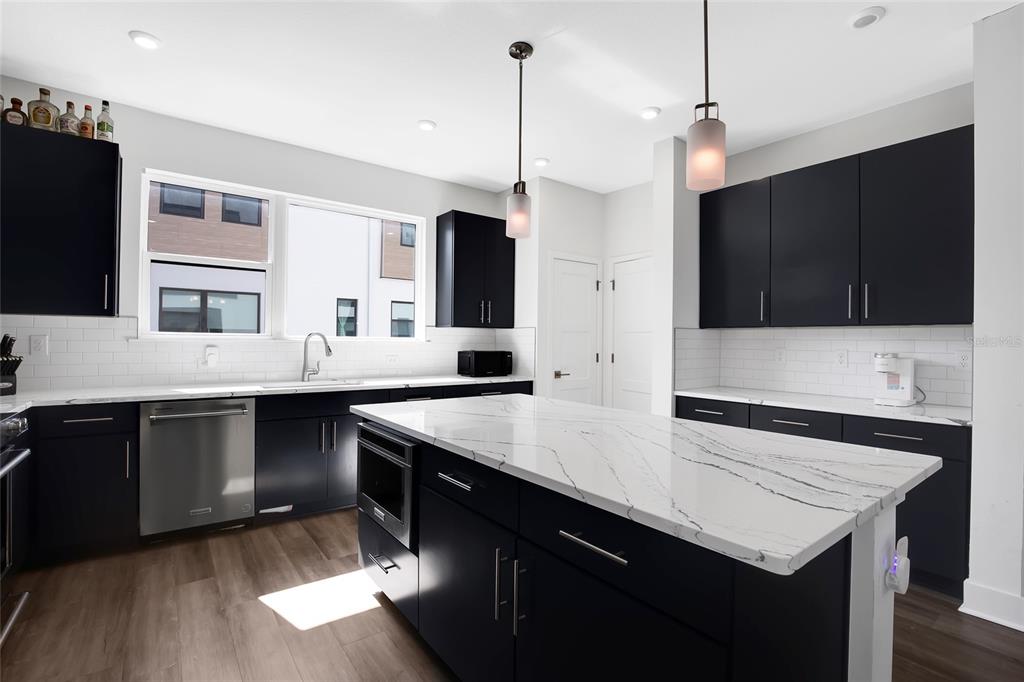 A modern kitchen features black cabinets, white quartz countertops, and a large central island — 2506 W CLEVELAND STREET UNIT 9, TAMPA, FL