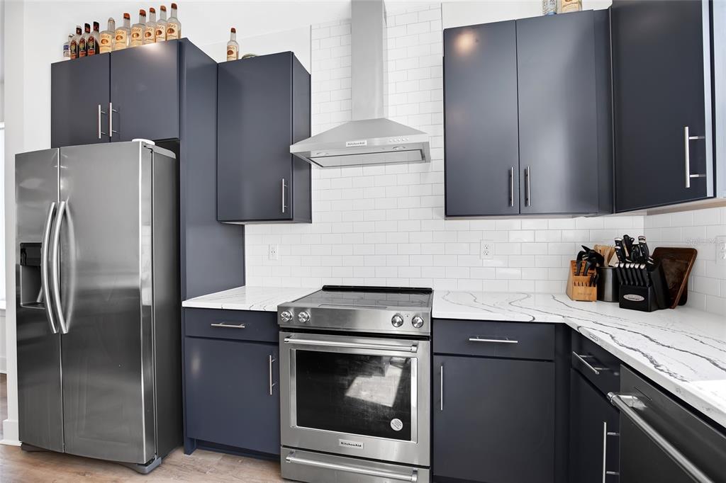 A kitchen features dark blue cabinets, stainless steel appliances, and white marble-look countertops — 2506 W CLEVELAND STREET UNIT 9, TAMPA, FL