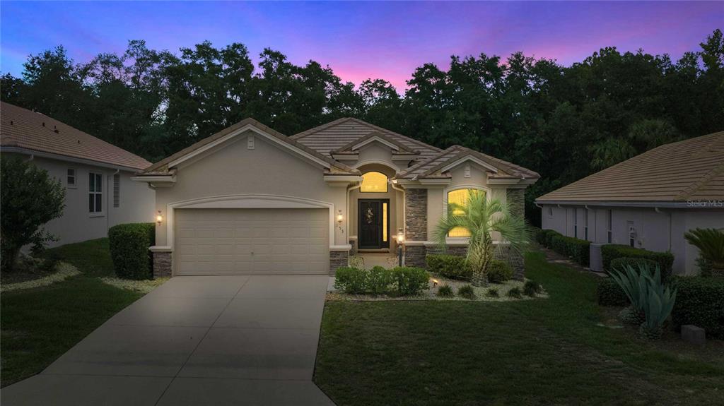 A single-story suburban house with a beige stucco exterior, a two-car garage, and a tiled roof — 155 W DOERR PATH, HERNANDO, FL