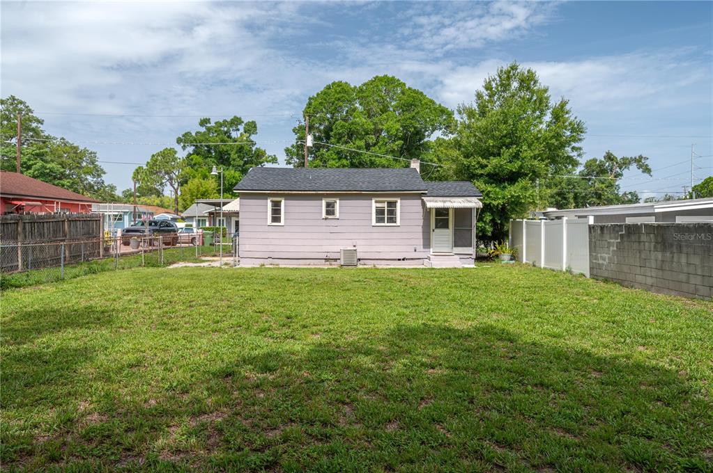 The exterior of a single-story house with light purple siding and a large grassy backyard — 3905 N CLEARFIELD AVE, TAMPA, FL