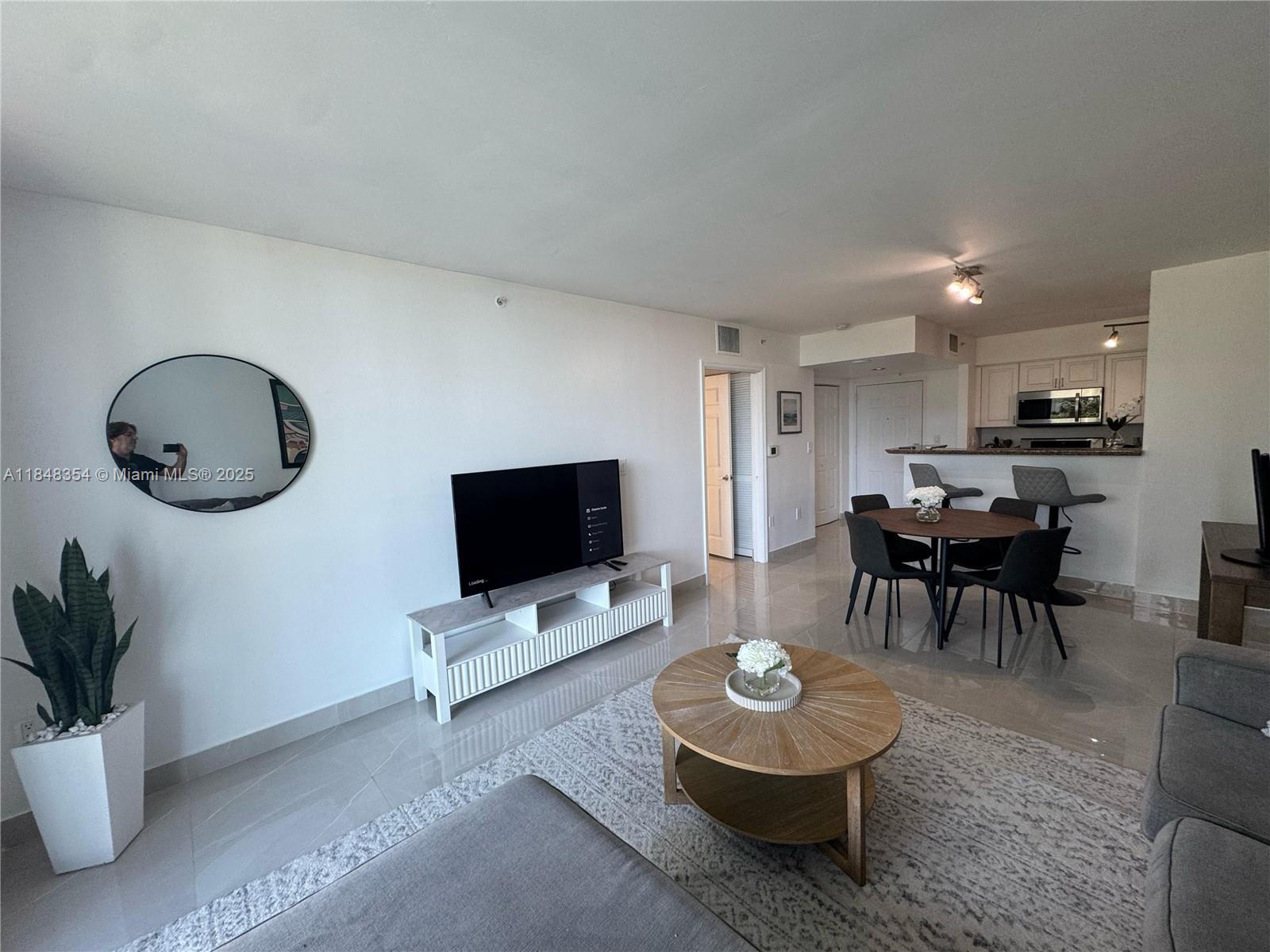 A living room and dining area feature tile floors, a round coffee table, and furniture — 1155 Brickell Bay Dr # 307, Miami FL 33131, MIAMI, FL