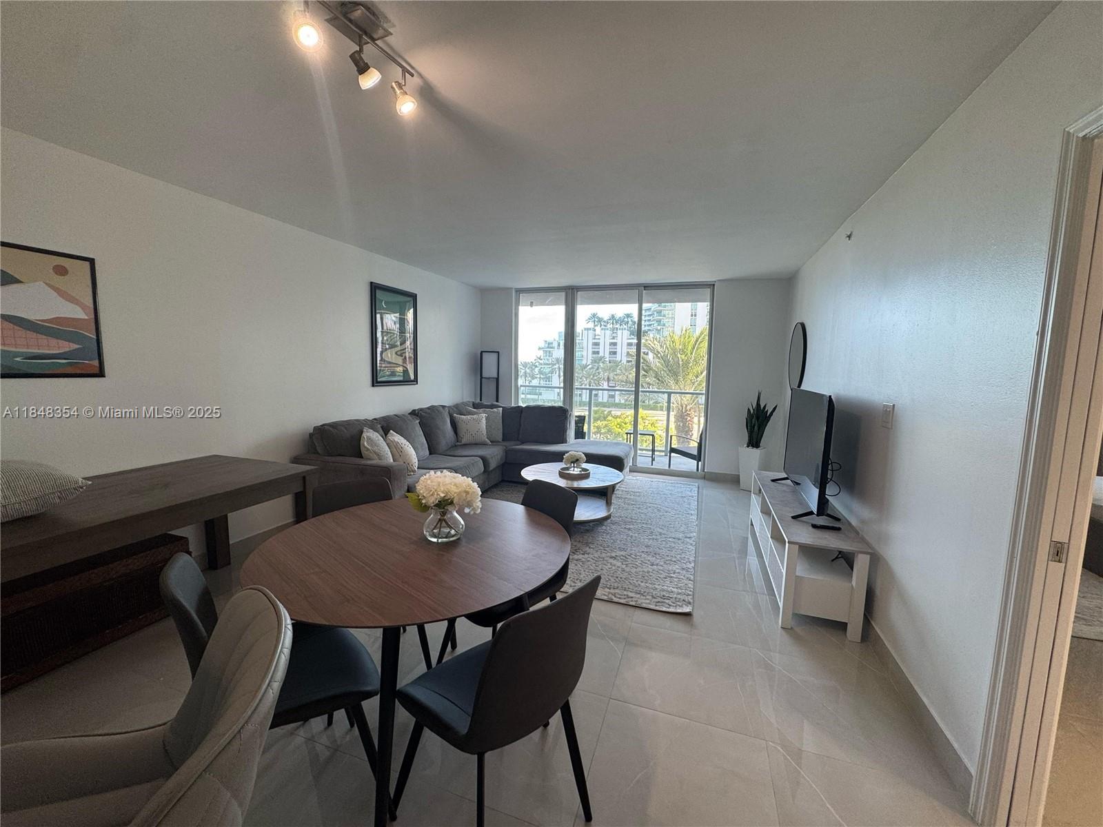 A living and dining area features tile floors, a sectional sofa, and a balcony view — 1155 Brickell Bay Dr # 307, Miami FL 33131, MIAMI, FL