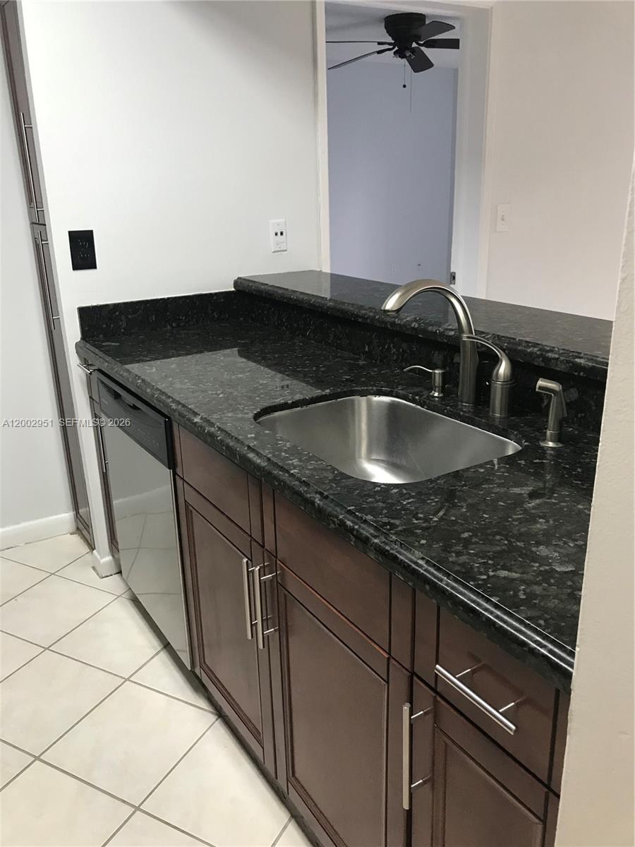 A kitchen features dark wood cabinets, black granite countertops, and a stainless steel sink — 7075 NW 186th St # C408, Hialeah FL 33015, HIALEAH, FL