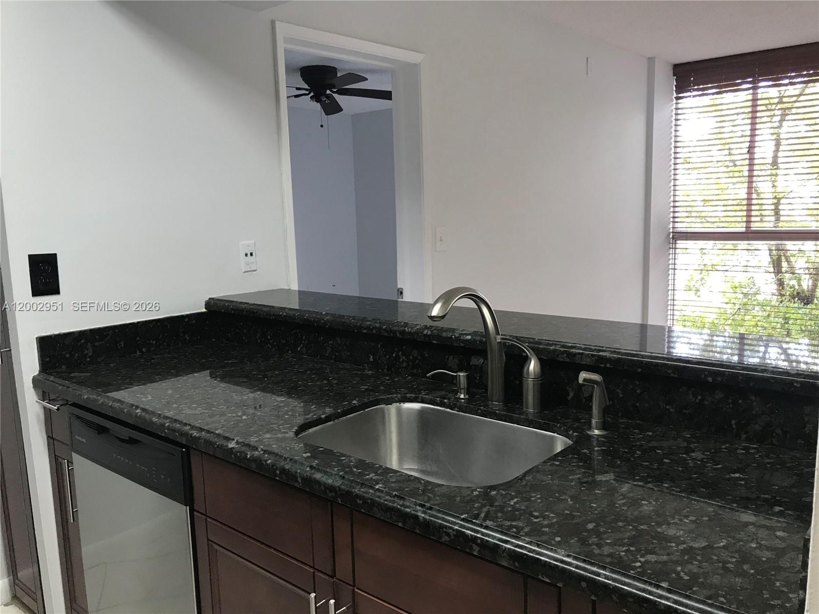 A kitchen features dark granite countertops, a stainless steel sink, and dark wood cabinets — 7075 NW 186th St # C408, Hialeah FL 33015, HIALEAH, FL