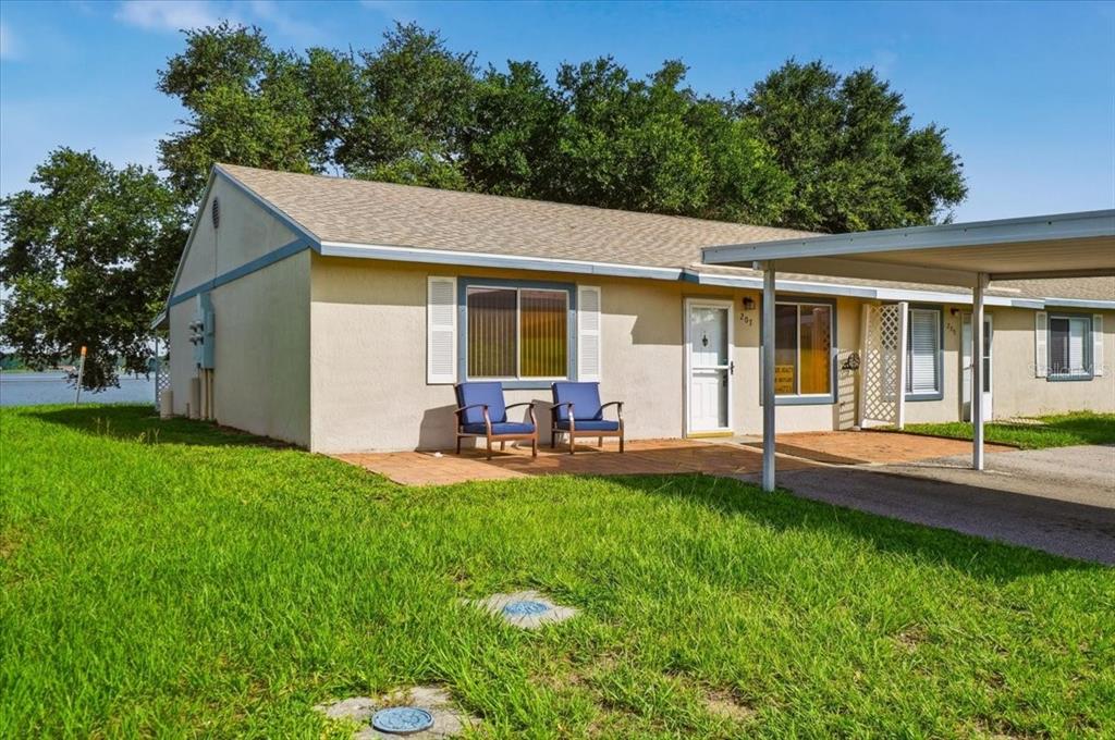 A single-story residential unit with a carport, patio, and lake view in the background — 207 WINTER RIDGE BOULEVARD UNIT 4, WINTER HAVEN, FL