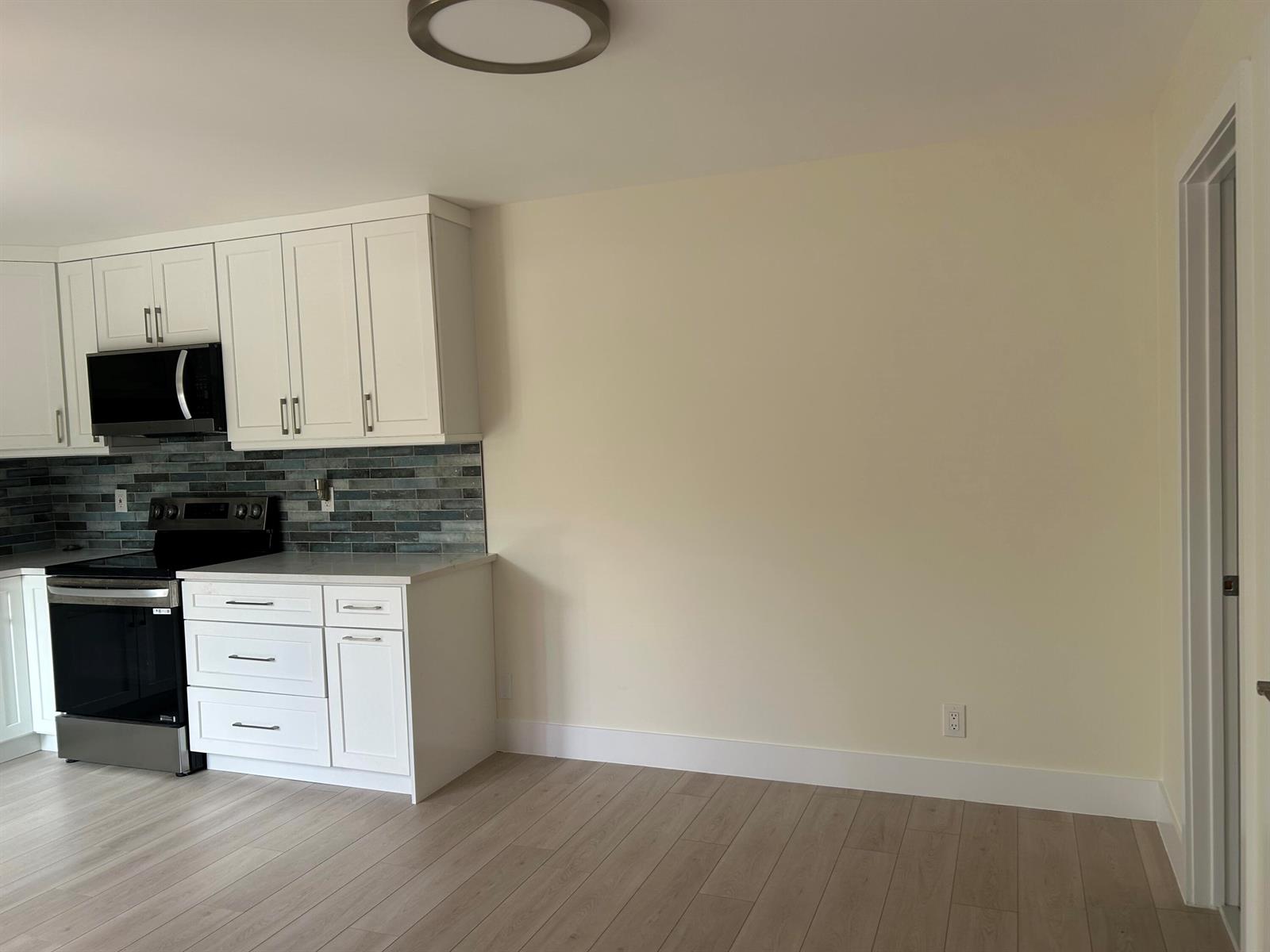 A kitchen with white cabinets, a black stove, and a blue tiled backsplash — 2802 SW 12th Street, Deerfield Beach FL 33442, DEERFIELD BEACH, FL