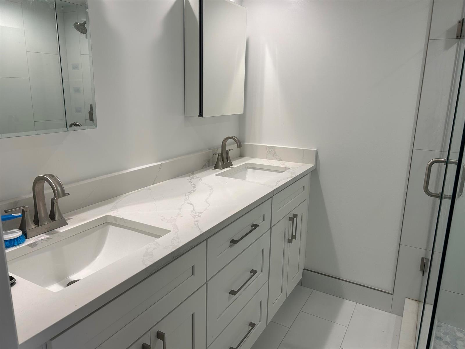 A modern bathroom features a double vanity with white cabinets and a marble-patterned countertop — 2802 SW 12th Street, Deerfield Beach FL 33442, DEERFIELD BEACH, FL