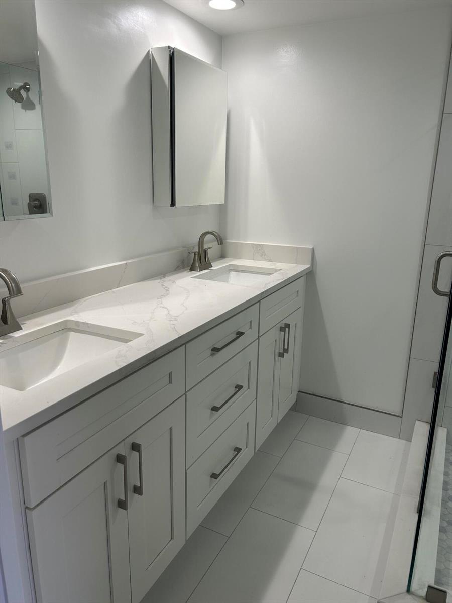 A modern bathroom features a white double vanity with a marble countertop and silver hardware — 2802 SW 12th Street, Deerfield Beach FL 33442, DEERFIELD BEACH, FL