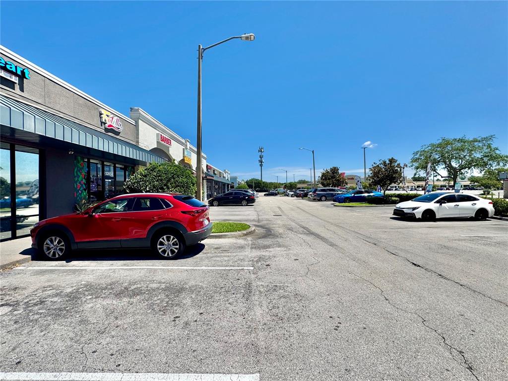 A red SUV is parked in front of a strip mall under a clear sky — 3283 S JOHN YOUNG PARKWAY, KISSIMMEE, FL