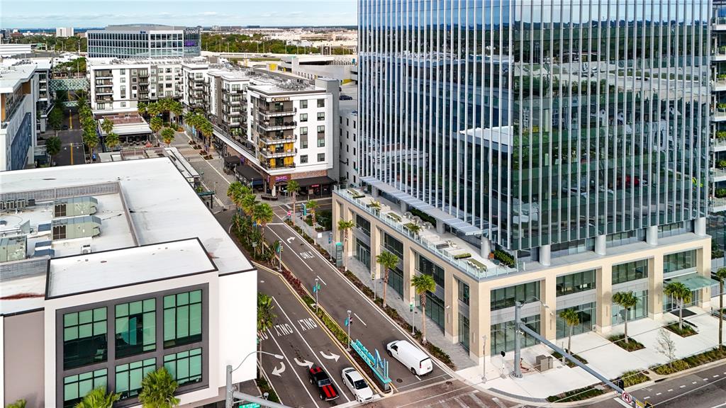 An aerial view shows a modern glass office building next to apartment complexes and streets — 3440 and 3426 W CYPRESS STREET, TAMPA, FL