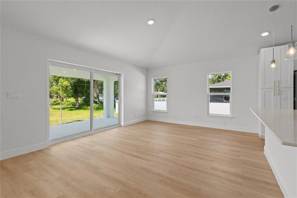 A bright room with light wood-look flooring, white walls, sliding glass doors, and two windows — 4315 HUNGARY ROAD, NORTH PORT, FL