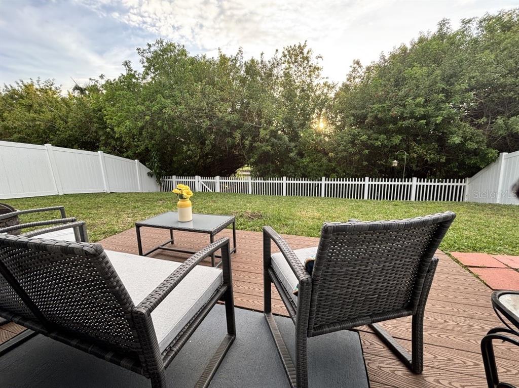 A patio with two wicker chairs and a small table overlooks a fenced backyard — 11521 SOUTHERN CREEK DRIVE, GIBSONTON, FL