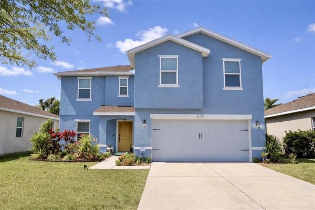A two-story blue house with a two-car garage and a yellow front door — 11521 SOUTHERN CREEK DRIVE, GIBSONTON, FL