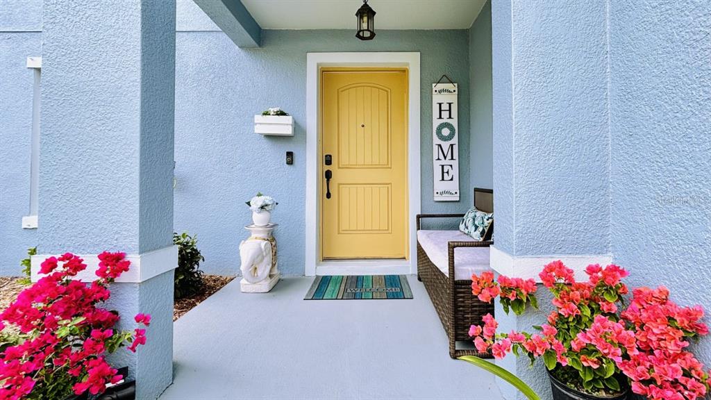 A front porch features a yellow door, a bench, and bright pink bougainvillea flowers — 11521 SOUTHERN CREEK DRIVE, GIBSONTON, FL