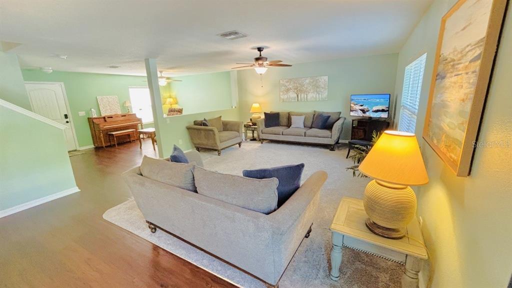 A living room features light green walls, carpeted flooring, two sofas, and a piano — 11521 SOUTHERN CREEK DRIVE, GIBSONTON, FL