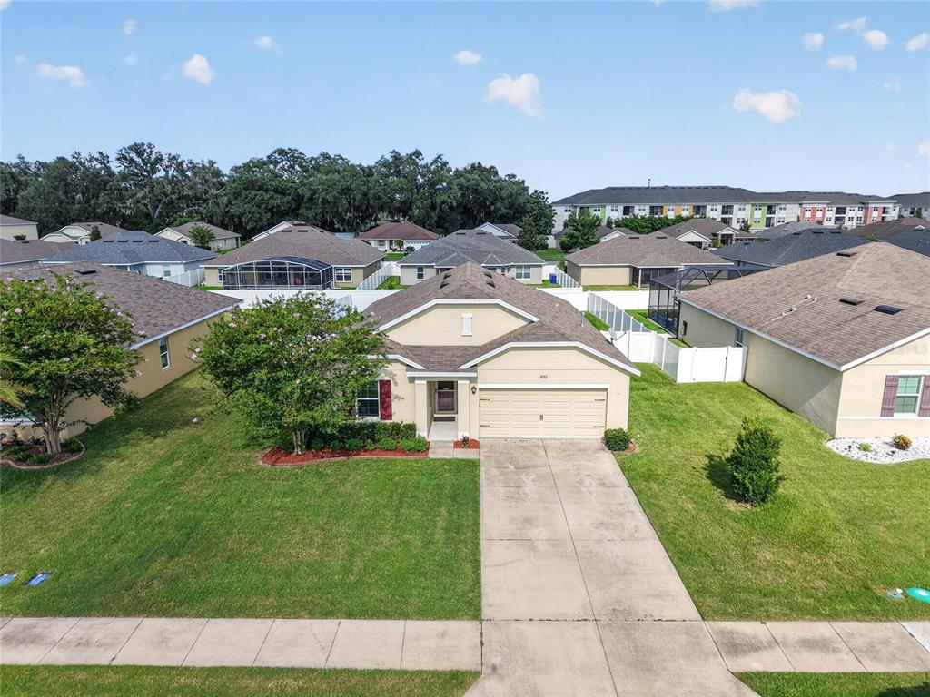 An aerial view of a single-story suburban house with a tan exterior and concrete driveway — 9785 PEPPER TREE TRAIL, WILDWOOD, FL