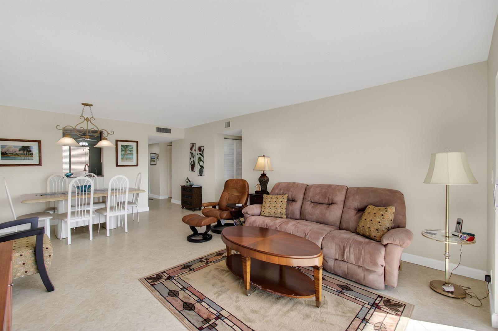 A living room and dining area with tile flooring, a brown sofa, and a rug — 7006 Huntington Lane # 404, Delray Beach FL 33446, DELRAY BEACH, FL
