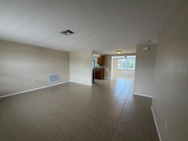 An open-concept living area features light-colored walls, beige tile flooring, and a view into the kitchen — 7539 GULF HIGHLANDS DRIVE, PORT RICHEY, FL