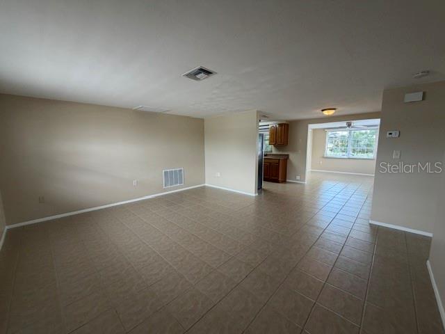 An open-concept living area features beige walls, tile flooring, and a view into the kitchen — 7539 GULF HIGHLANDS DRIVE, PORT RICHEY, FL