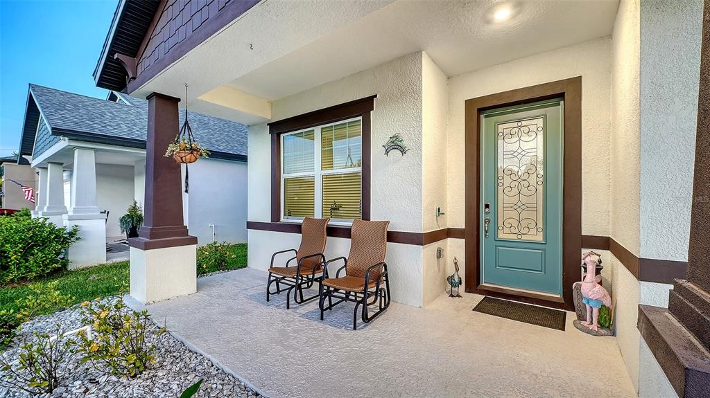 A front porch features two wicker chairs, a teal front door, and a hanging planter — 8234 TEA OLIVE TERRACE, PALMETTO, FL