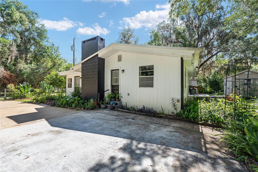 A white house with a black chimney and a concrete driveway surrounded by trees — 25140 NE 133RD PLACE, SALT SPRINGS, FL