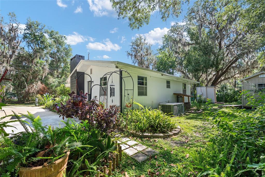 A white house with a dark chimney stands in a yard with trees and landscaping — 25140 NE 133RD PLACE, SALT SPRINGS, FL
