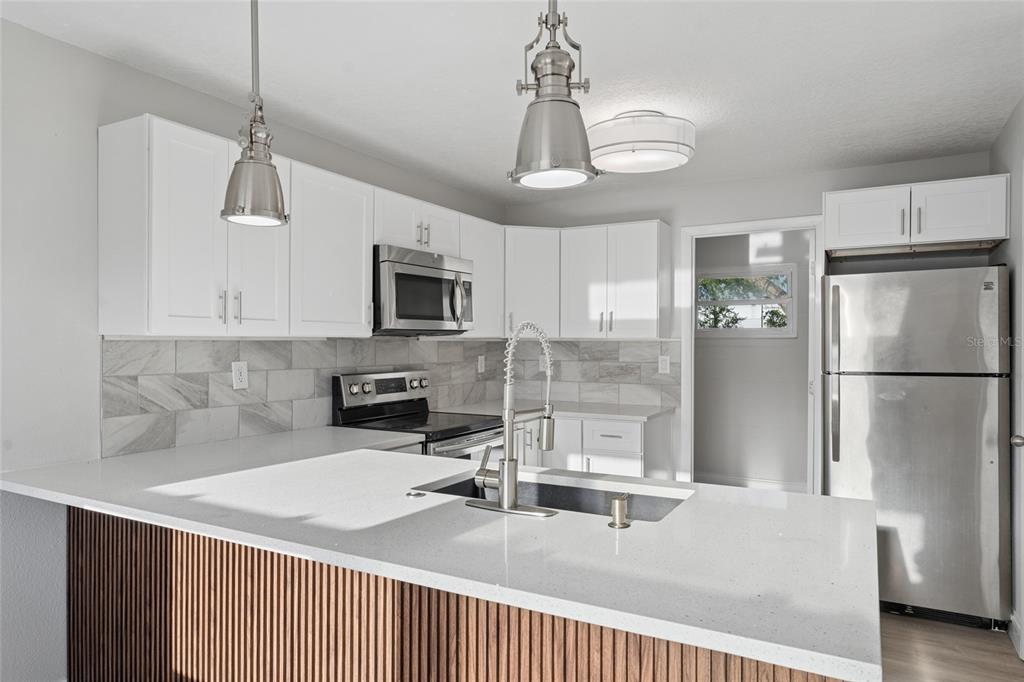 A kitchen features white cabinets, stainless steel appliances, a quartz countertop, and a slatted island — 2105 9TH STREET NE, WINTER HAVEN, FL