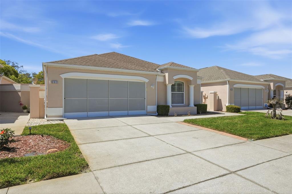 A single-story house with a beige stucco exterior, a two-car garage, and a concrete driveway — 363 ROYAL PALM WAY, SPRING HILL, FL