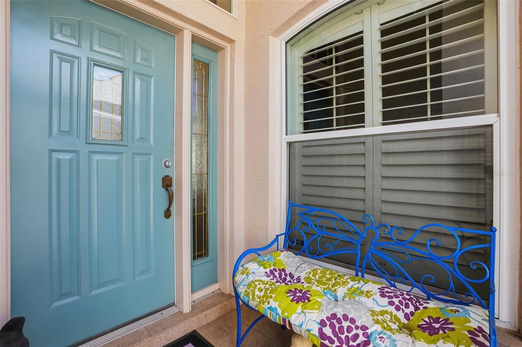 A light blue front door sits next to a window with a blue metal bench — 363 ROYAL PALM WAY, SPRING HILL, FL