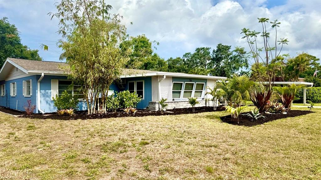 A single-story blue house with a white roof and landscaping sits on a grassy lot — 716 50TH STREET COURT W, BRADENTON, FL