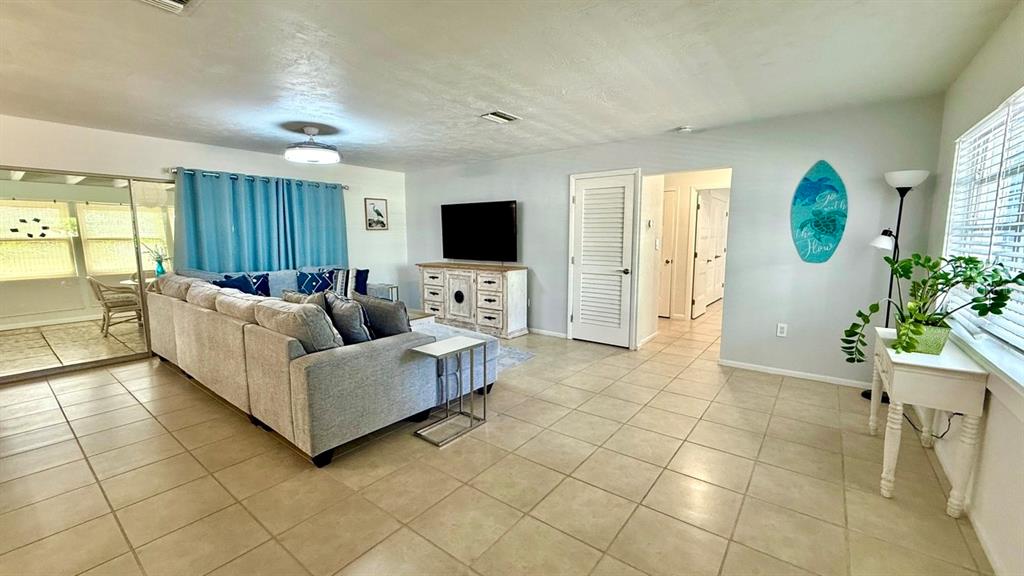 A living room features a sectional sofa, a television on a cabinet, and tile flooring — 716 50TH STREET COURT W, BRADENTON, FL