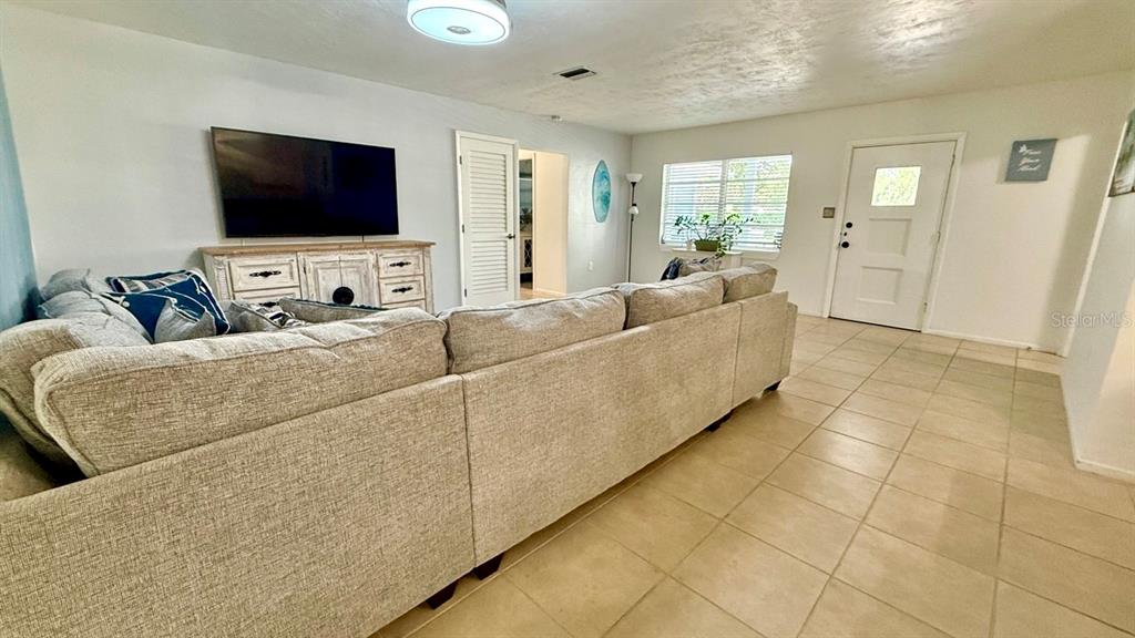 A living room features a large sectional sofa, a television on a console, and tile flooring — 716 50TH STREET COURT W, BRADENTON, FL