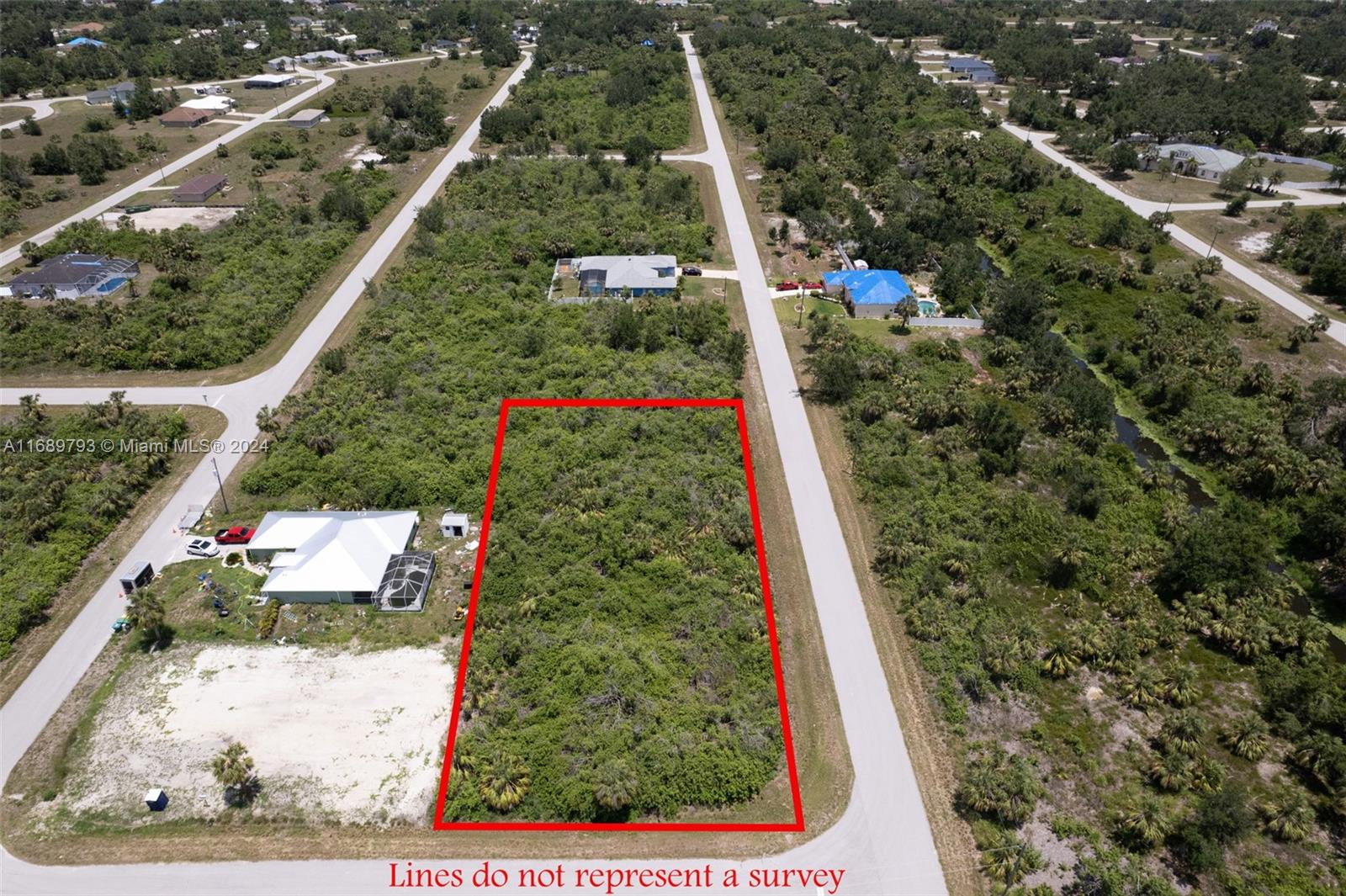 An aerial view shows a rectangular, undeveloped lot outlined in red between two paved roads — PORT CHARLOTTE, FL