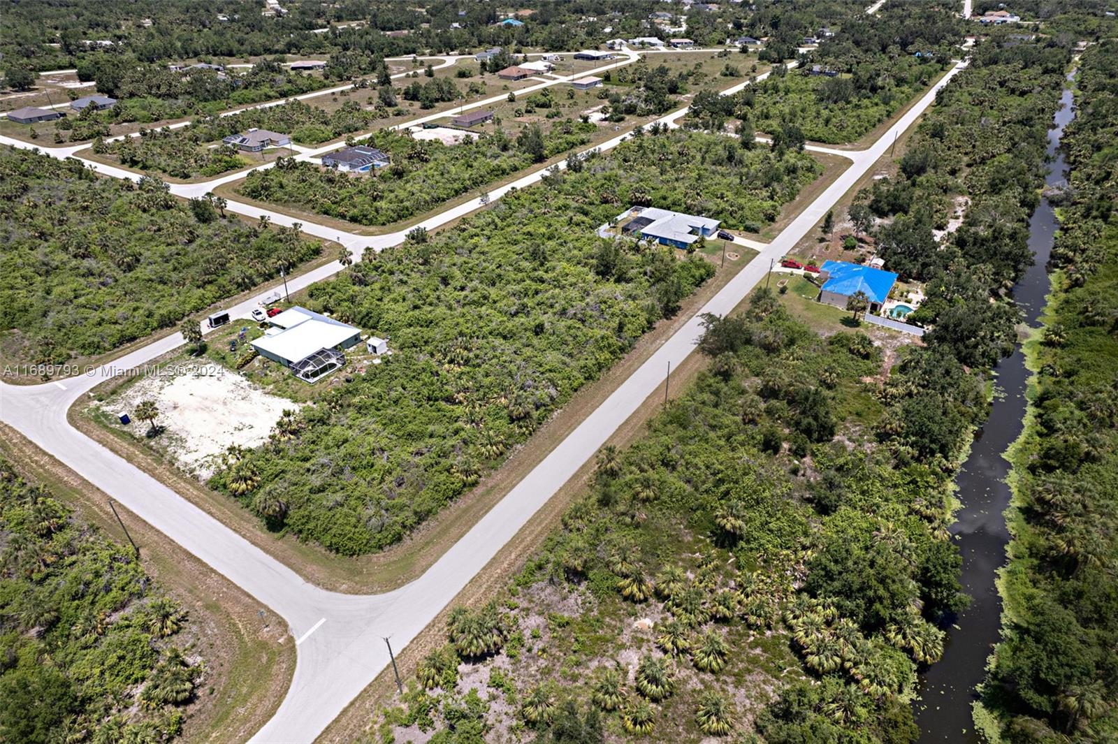 An aerial view shows houses scattered across a rural landscape with a canal nearby — PORT CHARLOTTE, FL