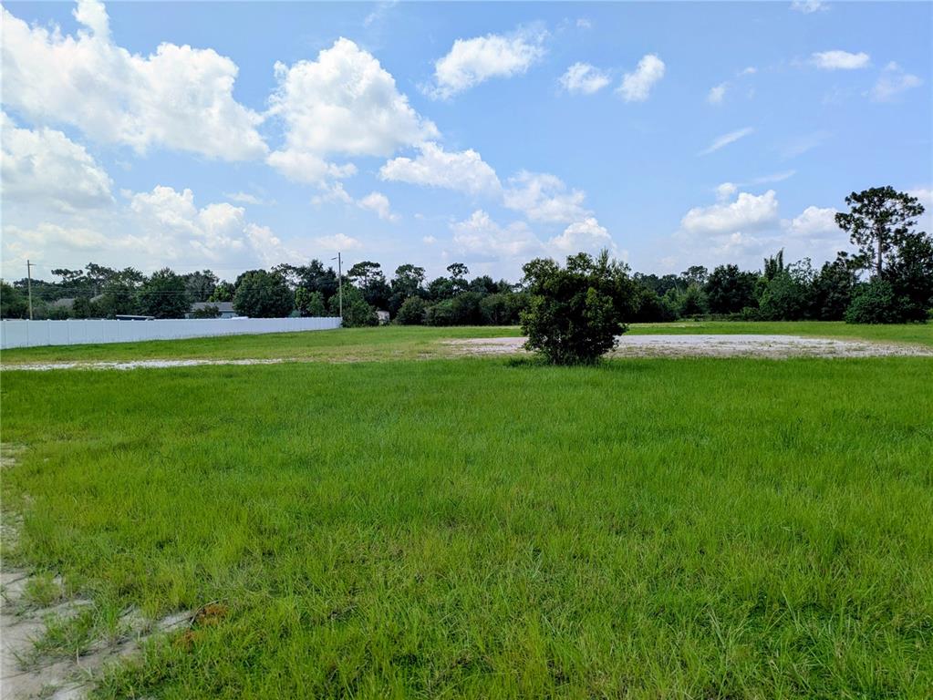 A large, grassy vacant lot features a single tree and a white fence in back — CORD AVENUE, ST CLOUD, FL