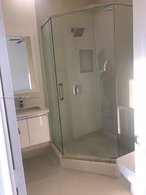A modern bathroom features a glass-enclosed corner shower, a white vanity, and light-colored tile flooring — 6316 NW 105th Pl # 0, Miami FL 33178, MIAMI, FL