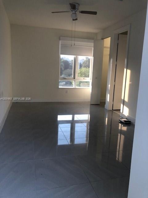 An empty bedroom features large gray floor tiles, a ceiling fan, and a window — 6316 NW 105th Pl # 0, Miami FL 33178, MIAMI, FL