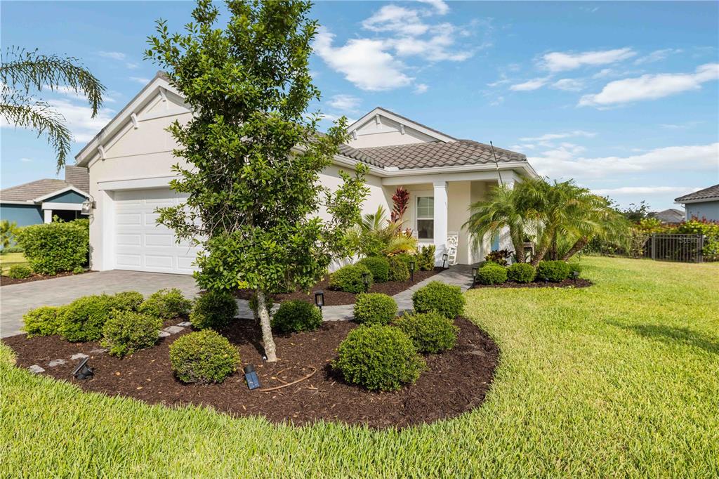A single-story house with a white exterior, a tiled roof, and landscaped front yard — 2669 STAR APPLE WAY, SARASOTA, FL