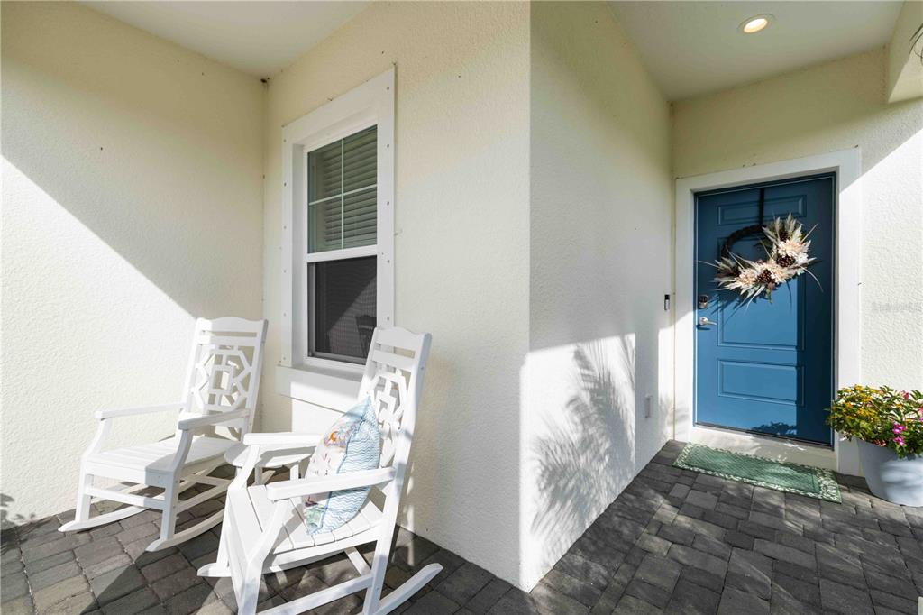 A front porch features two white rocking chairs, a blue door with a wreath, and pavers — 2669 STAR APPLE WAY, SARASOTA, FL