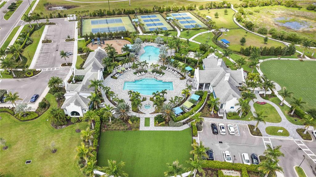 An aerial view shows a community clubhouse with swimming pools, tennis courts, and parking lots — 2669 STAR APPLE WAY, SARASOTA, FL