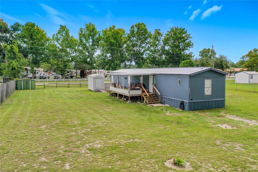 A blue mobile home with a covered porch sits on a large, grassy lot — 1400 NW 12TH LANE, LAKE PANASOFFKEE, FL