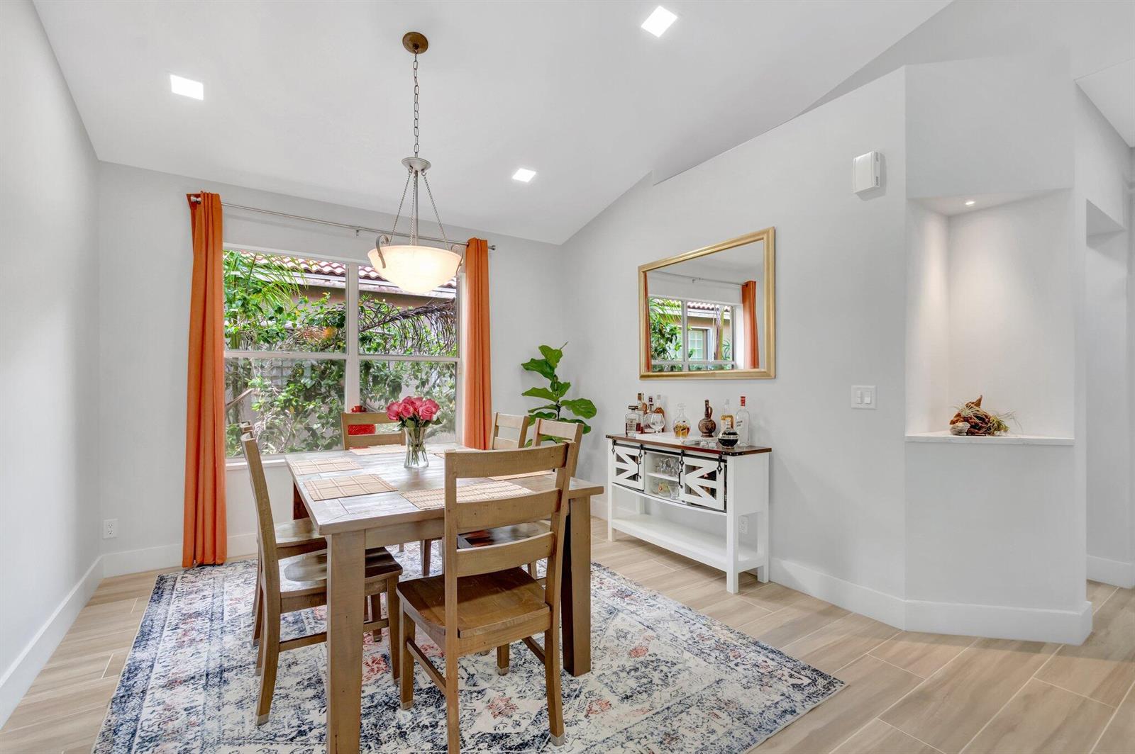 A dining room features a wooden table, chairs, a bar cabinet, and orange window curtains — 9640 Cherry Blossom Court, Boynton Beach FL 33437, BOYNTON BEACH, FL