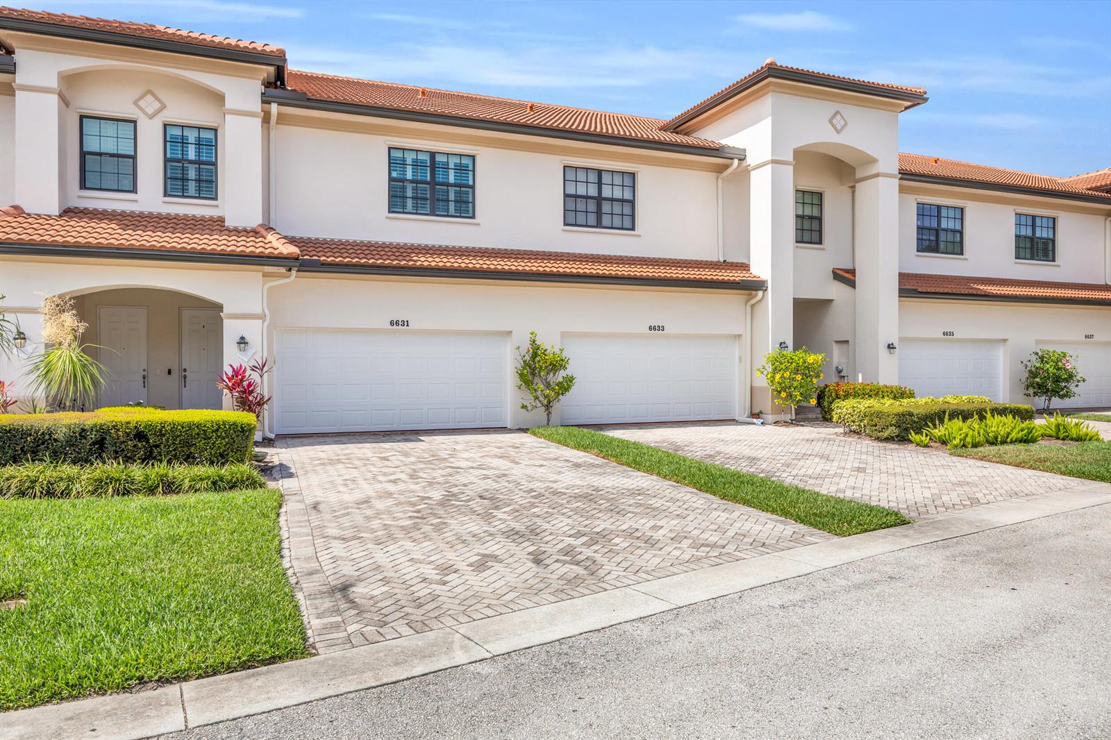 A row of two-story townhouses with white stucco walls, tile roofs, and paved driveways — 6631 SE Woodmill Pond Lane, Stuart FL 34997, STUART, FL
